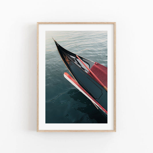 Framed Gondola photo on calm water against a plain white wall.