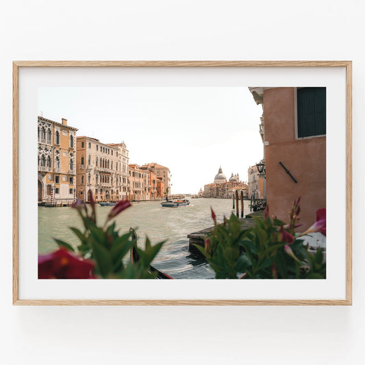 A framed photo titled Grand Canal depicting Venices canal with buildings and flowers in the foreground.