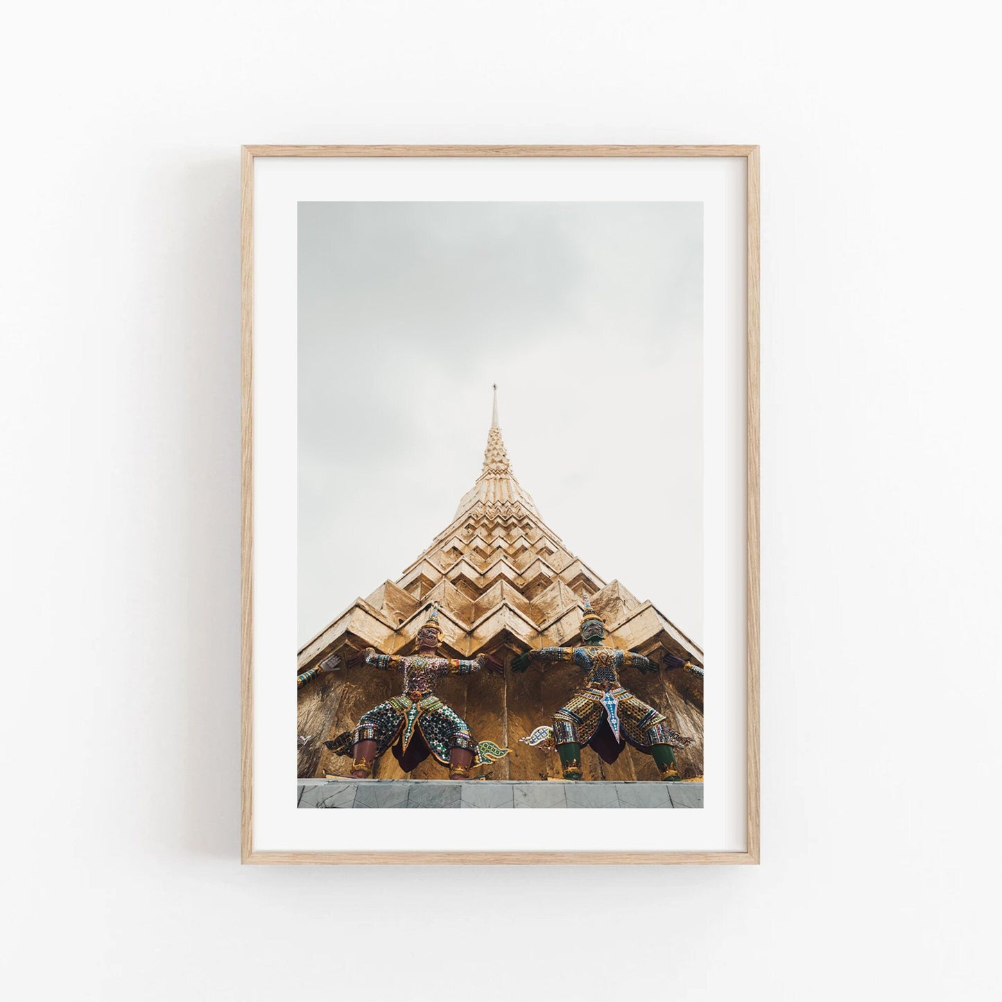 Framed photo of two statues beneath a golden temple spire with a light sky. Product: Grand Palace I.