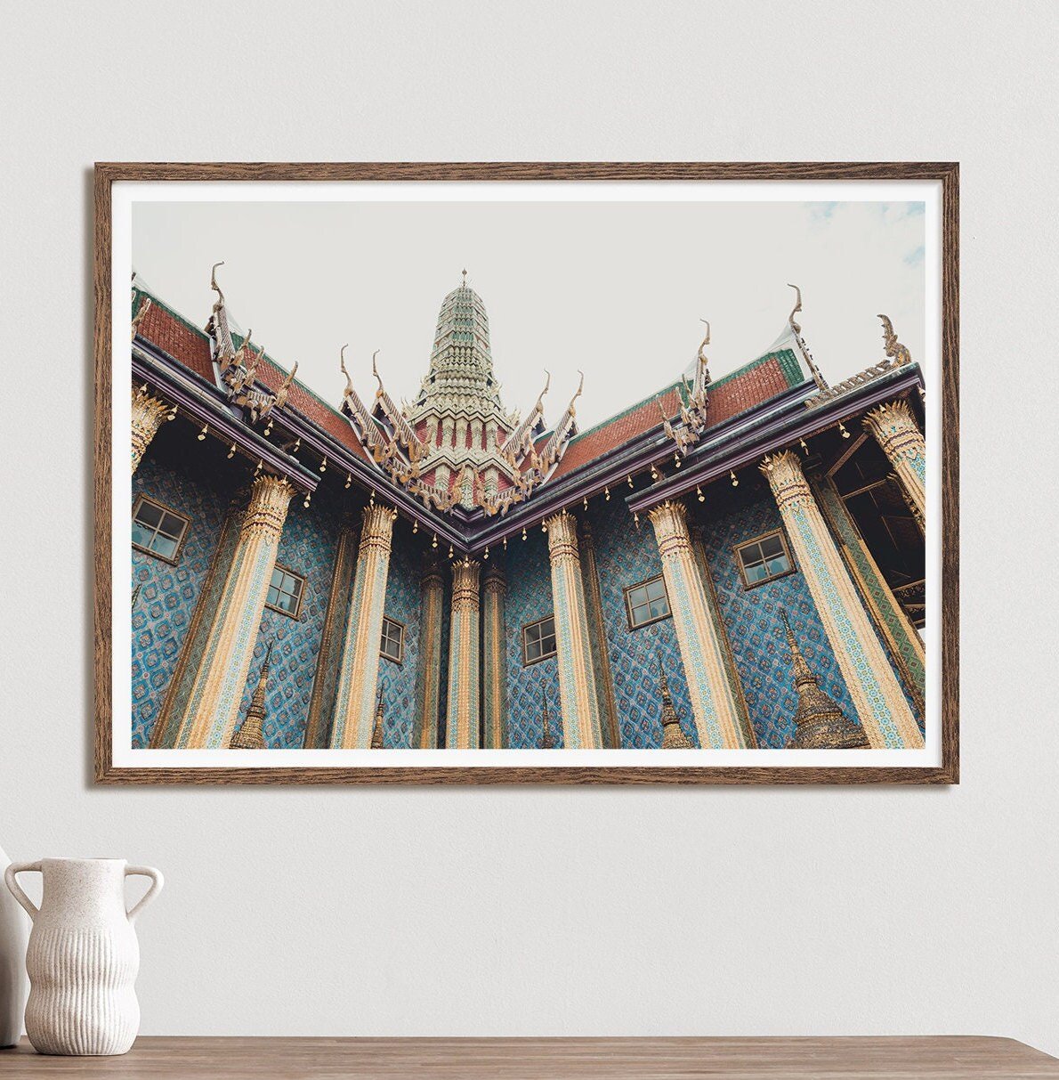 Framed Grand Palace IV photo of a Thai temple with an ornate roof and columns, set against a neutral wall with a white vase.