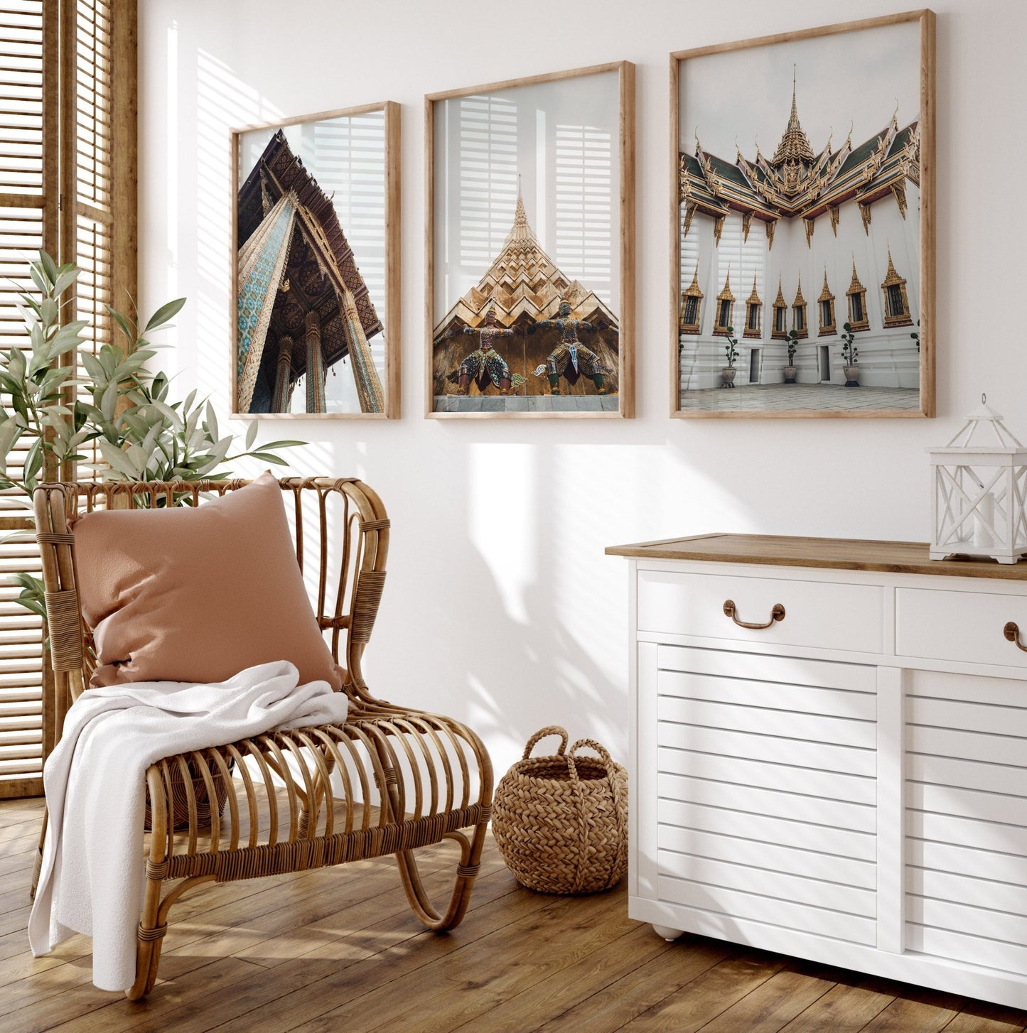 Cozy room with a wicker chair, cushion, throw, Grand Palace - Set of 3 photos on the wall, white cabinet, and sunlight.