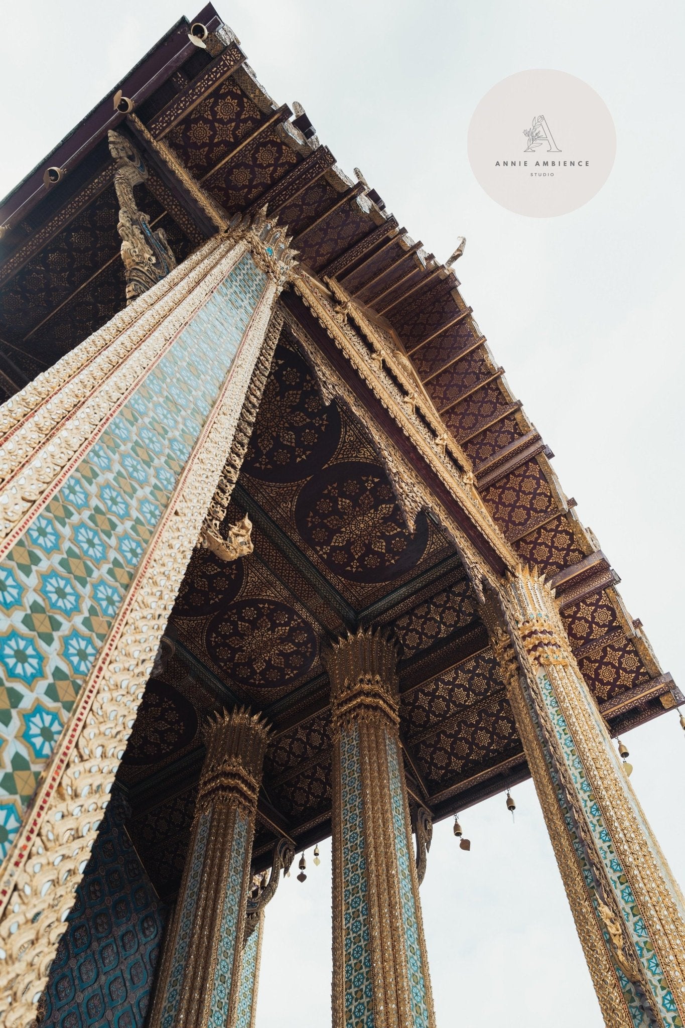 Low-angle view of the intricate Grand Palace ceiling with ornate blue and gold pillars.