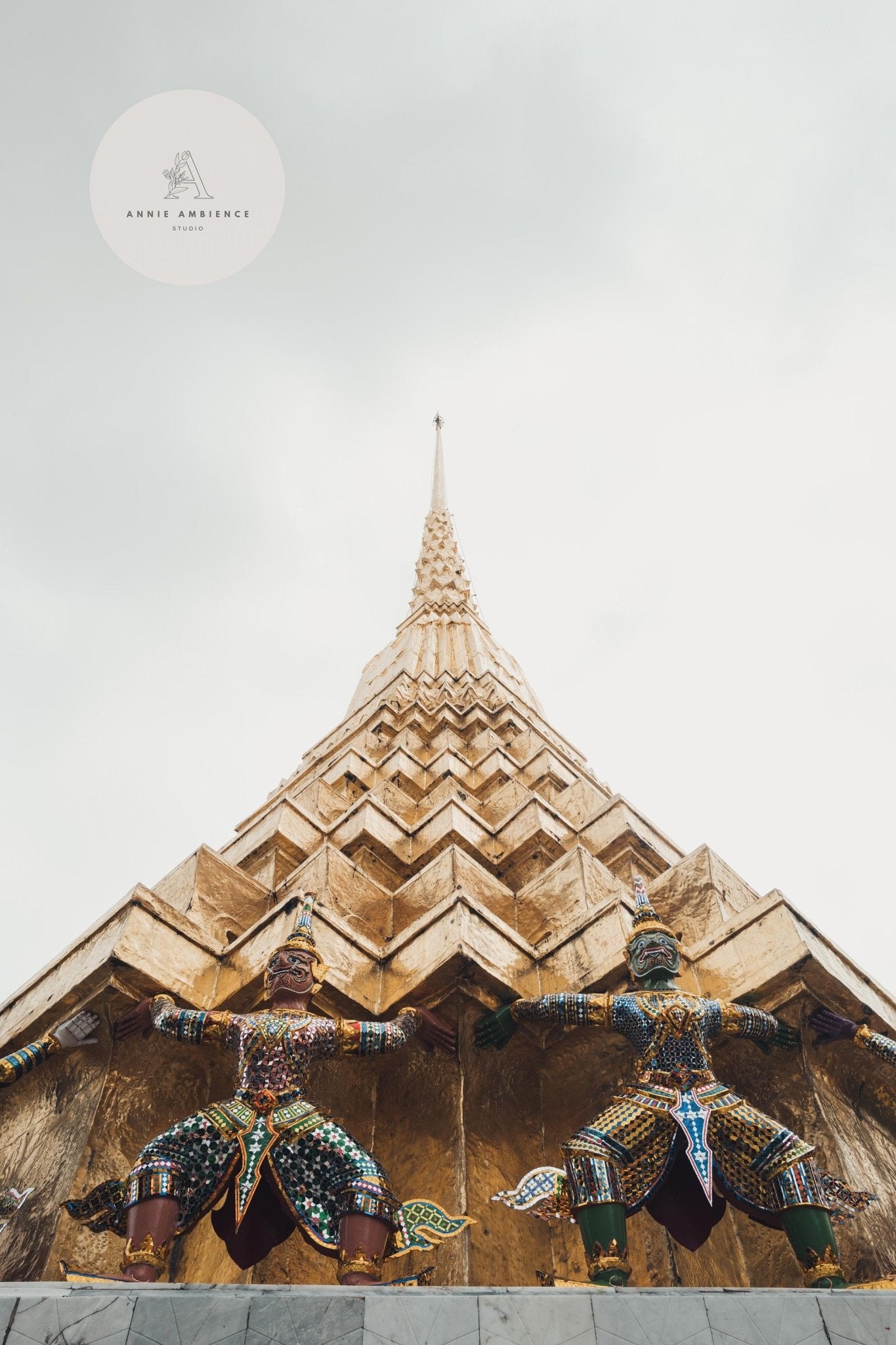 Low-angle view of a golden spire with guardian statues under a cloudy sky from the Grand Palace - Set of 3.
