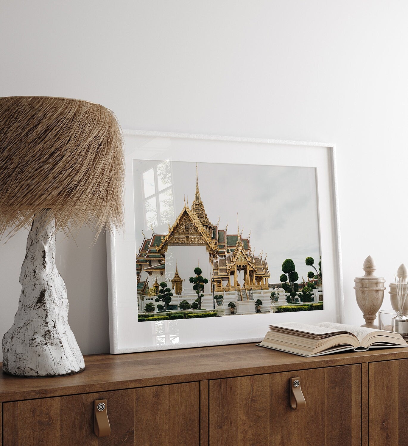 Grand Palace VII framed photo on a wooden cabinet with an open book and unique lamp beside it.