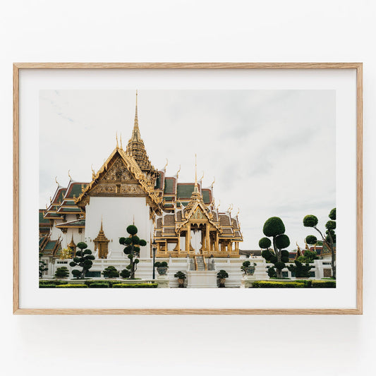 Framed photo of Grand Palace VII: ornate temple with golden details, manicured trees, and cloudy sky.