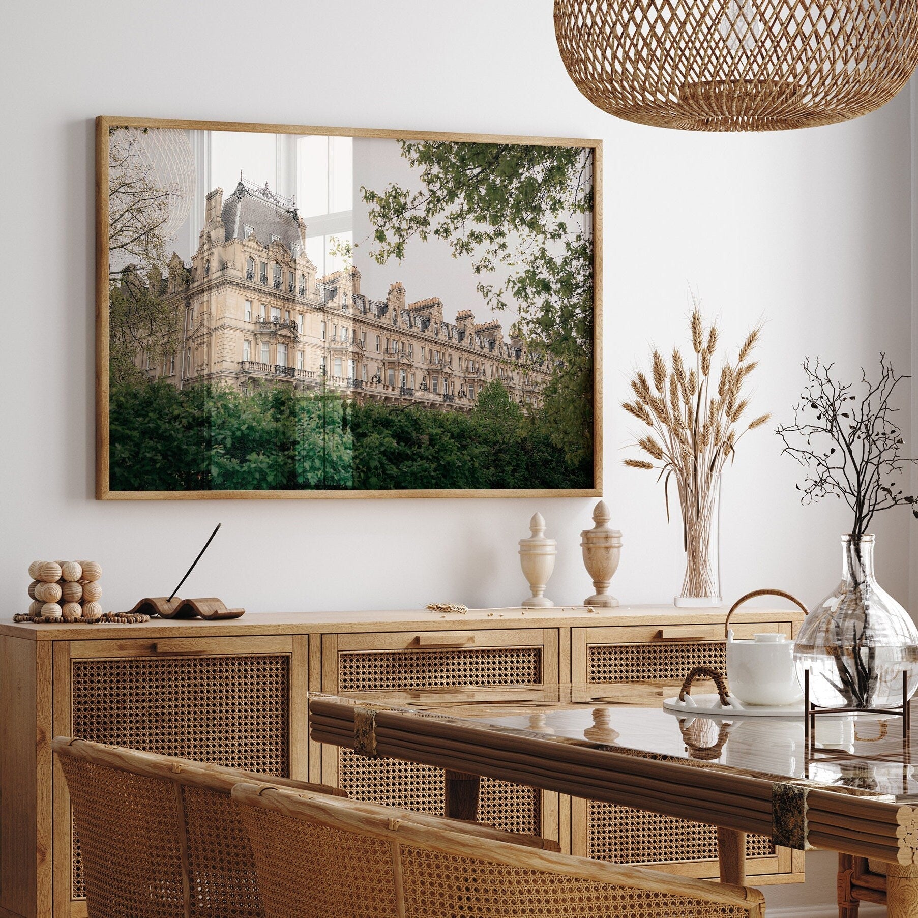 A cozy dining room with Grandeur rattan furniture, a framed cityscape, and a woven pendant light.