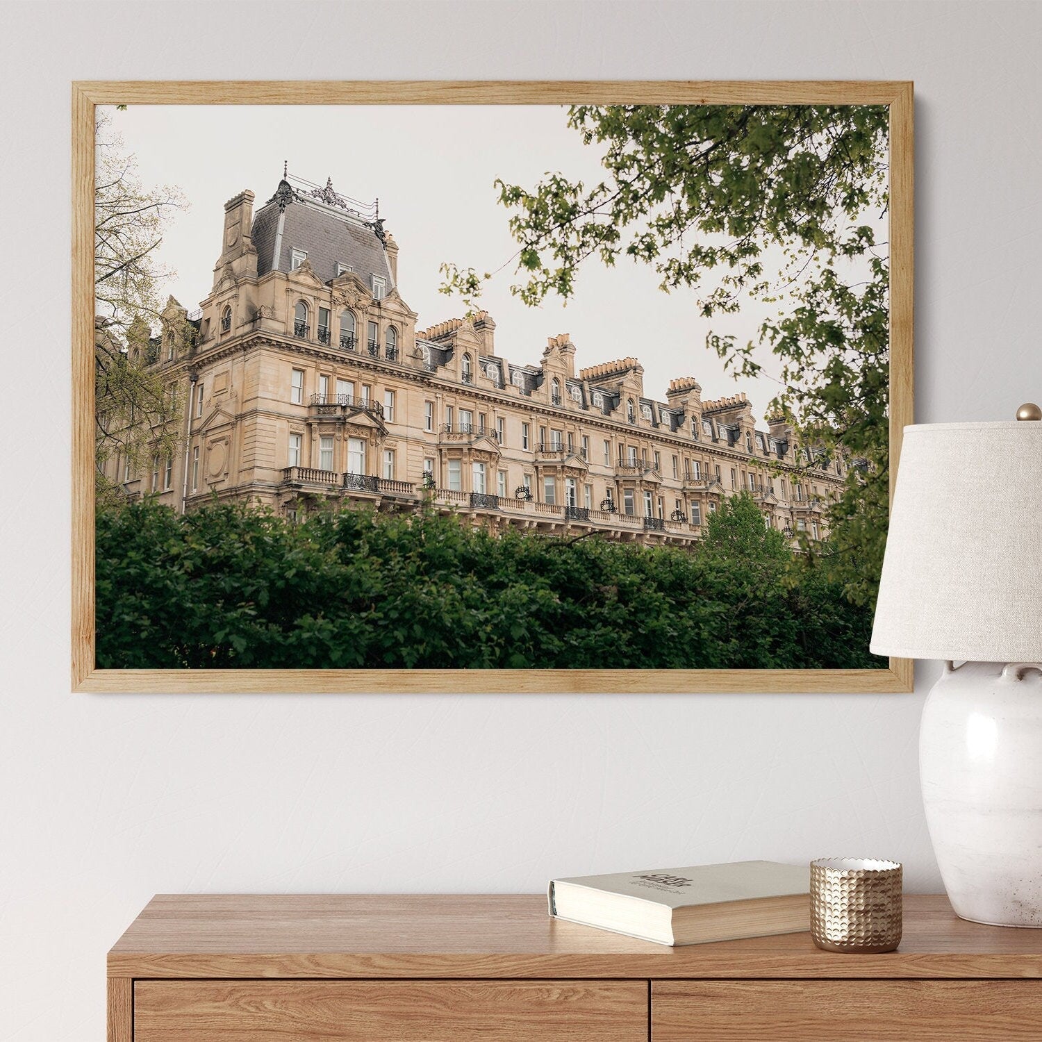 The Grandeur photo depicts a historic building with trees, hanging above a wooden dresser with a lamp and book.
