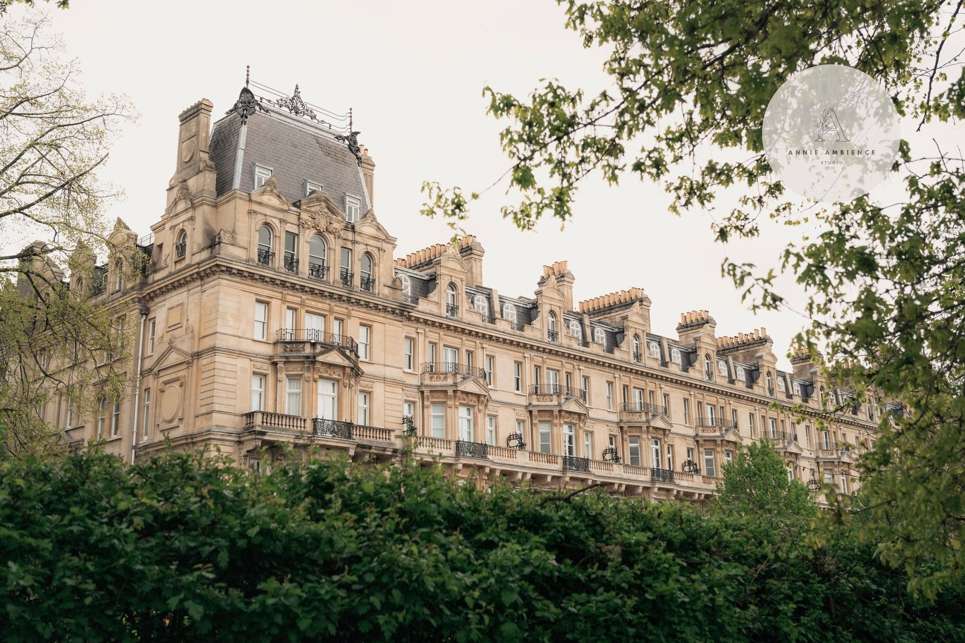The Grandeur: a historic building with ornate architecture, encircled by lush green trees and bushes.