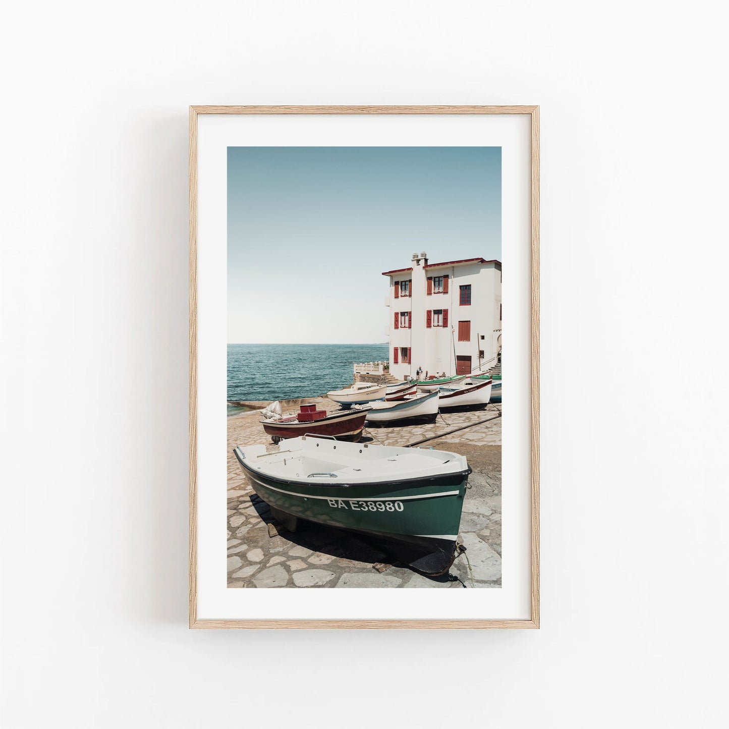 Framed photo Guethary: boats docked by a white building on a stone pier under clear seaside skies.