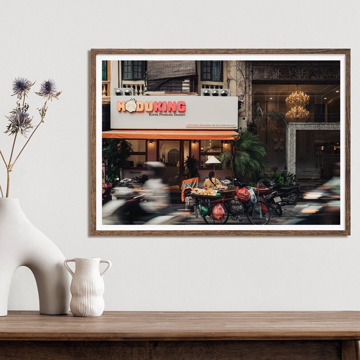 The Hanoi Street Blur photo shows a restaurant and street traffic on a white wall with decorative vases nearby.