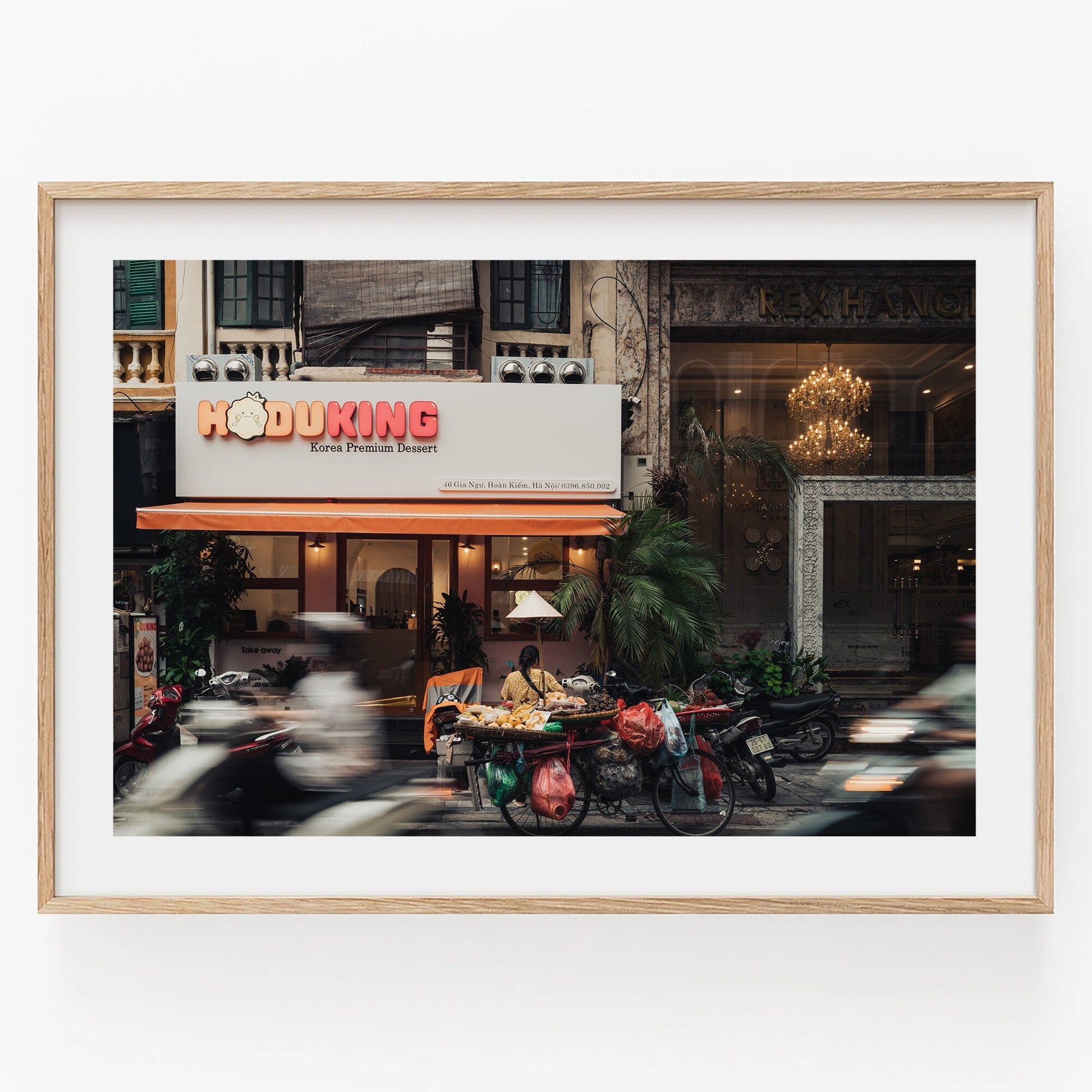 Hanoi Street Blur: A framed scene of Hoduking pancake shop with vehicles in motion.