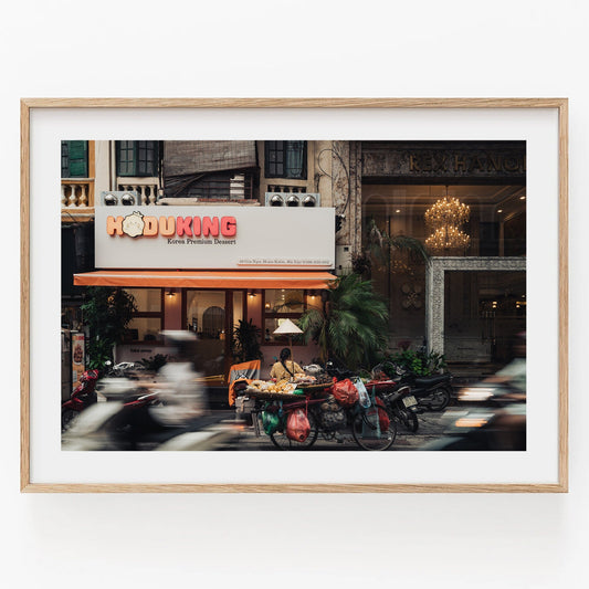 Hanoi Street Blur: A framed scene of Hoduking pancake shop with vehicles in motion.