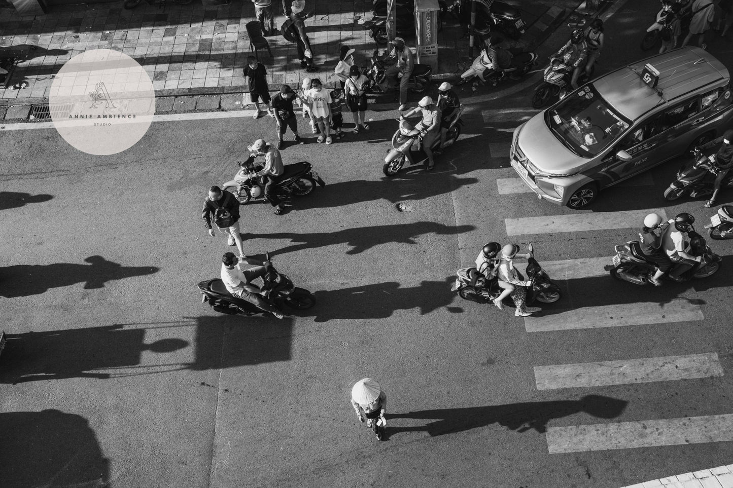 An aerial view from Hanoi Street Crossing Black and White shows a bustling street with pedestrians, scooters, and a car.