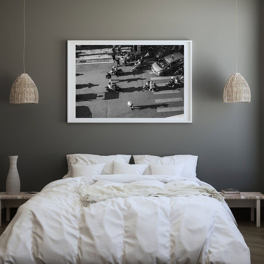 Minimalist bedroom with a white bed, wicker lamps, and a Hanoi Street Crossing black-and-white photo on the wall.