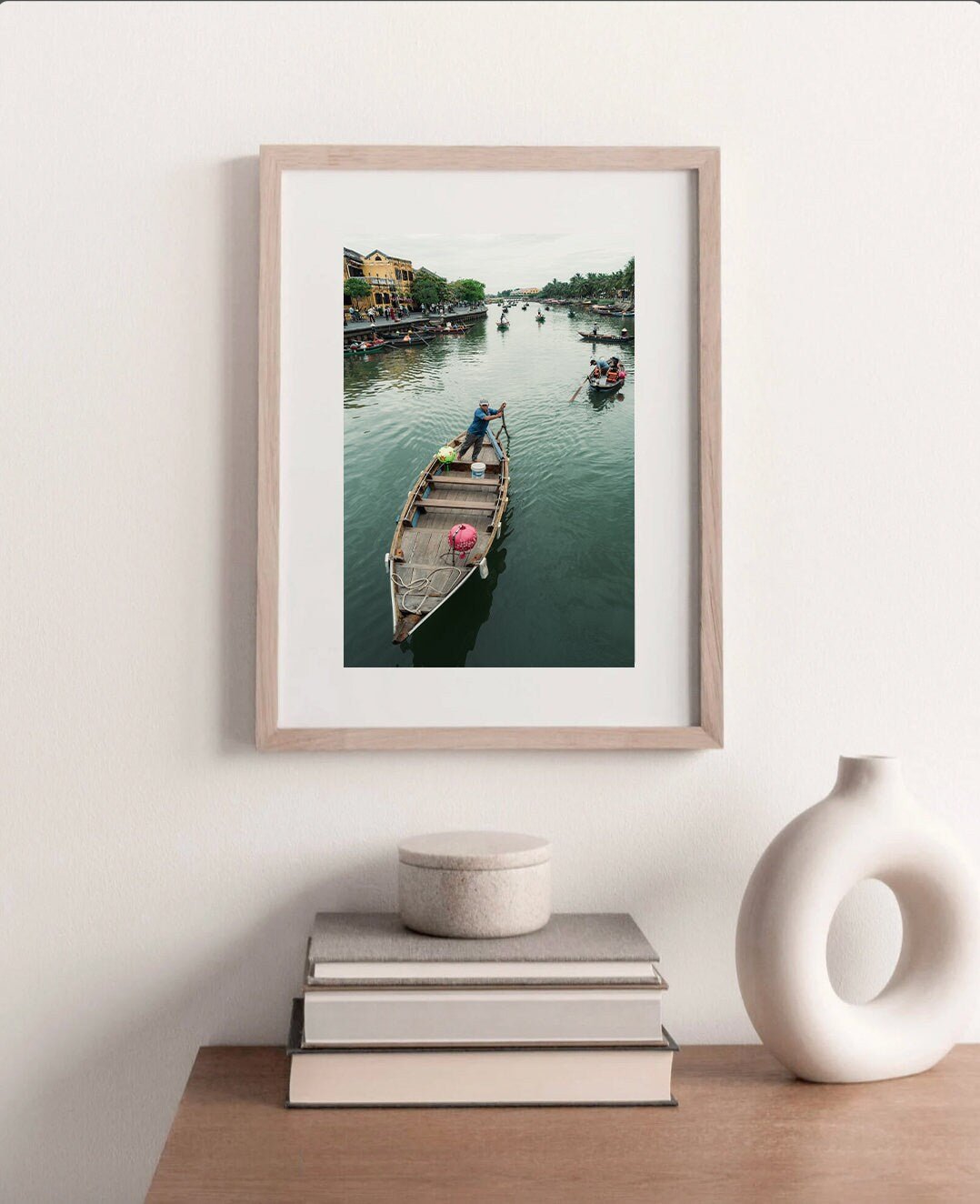 Hoi An Row photo framed on a shelf with books and a decorative vase.