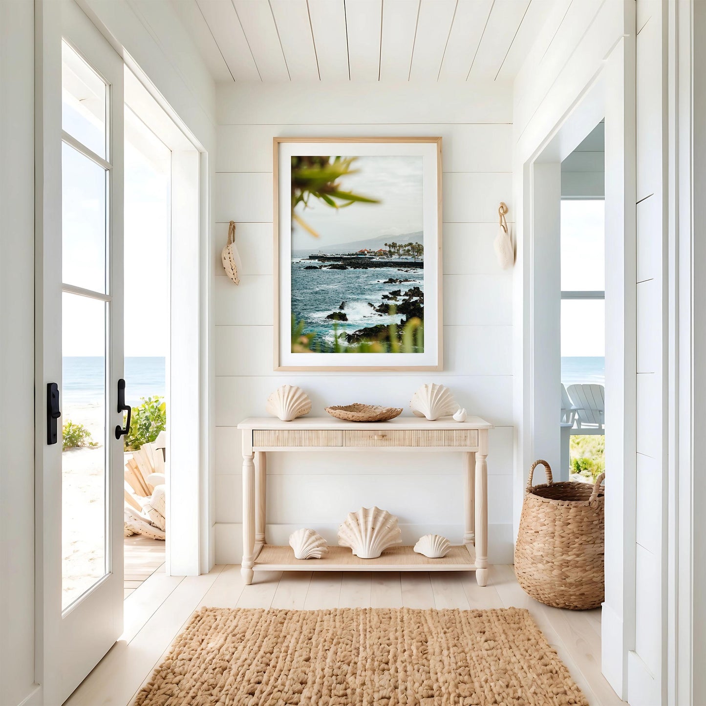 Coastal Glimpse: Bright hallway with coastal decor, woven rug, seashells, and framed ocean view leading to a beach patio.