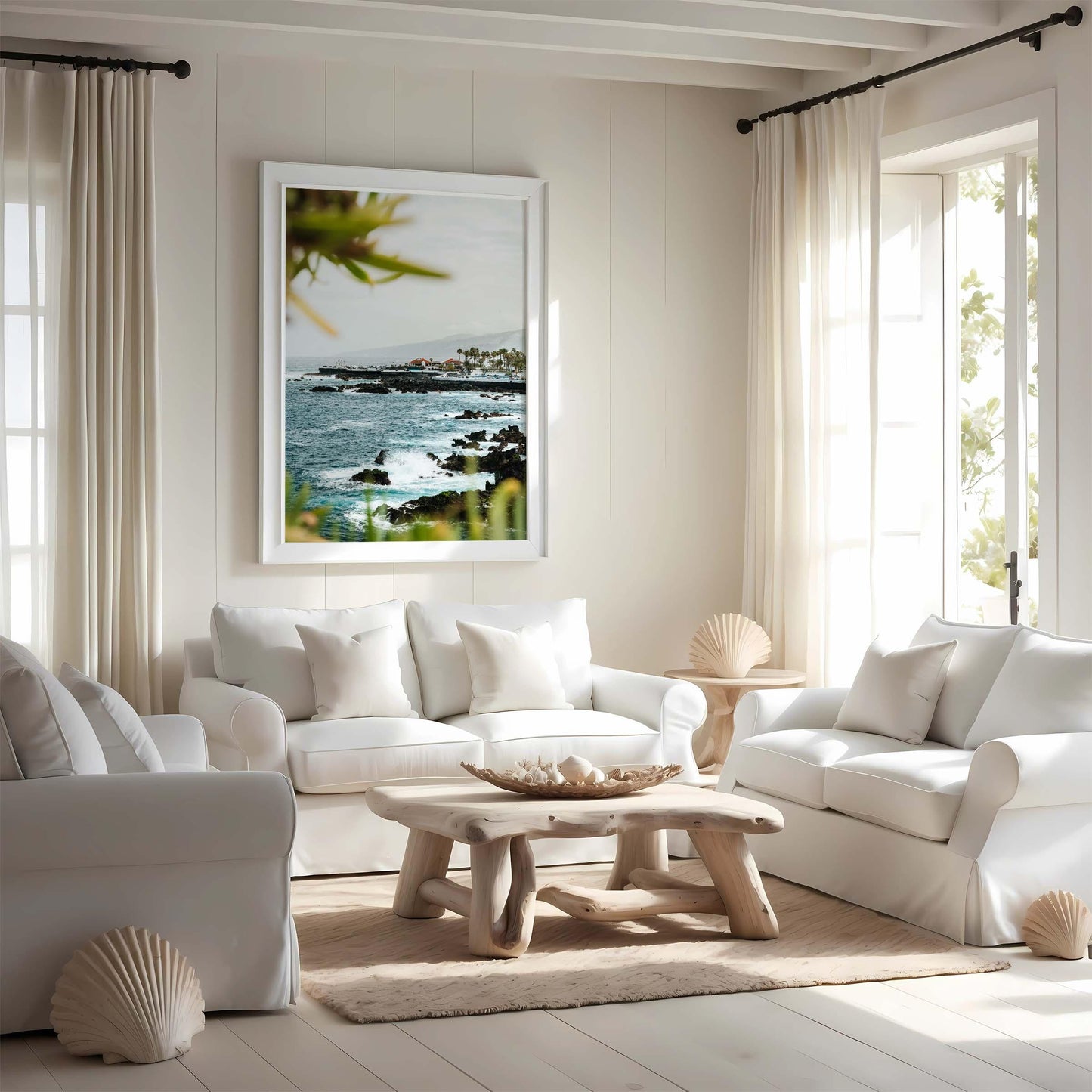 Bright living room with white sofas, wooden table, and the Coastal Glimpse ocean photo on the wall.
