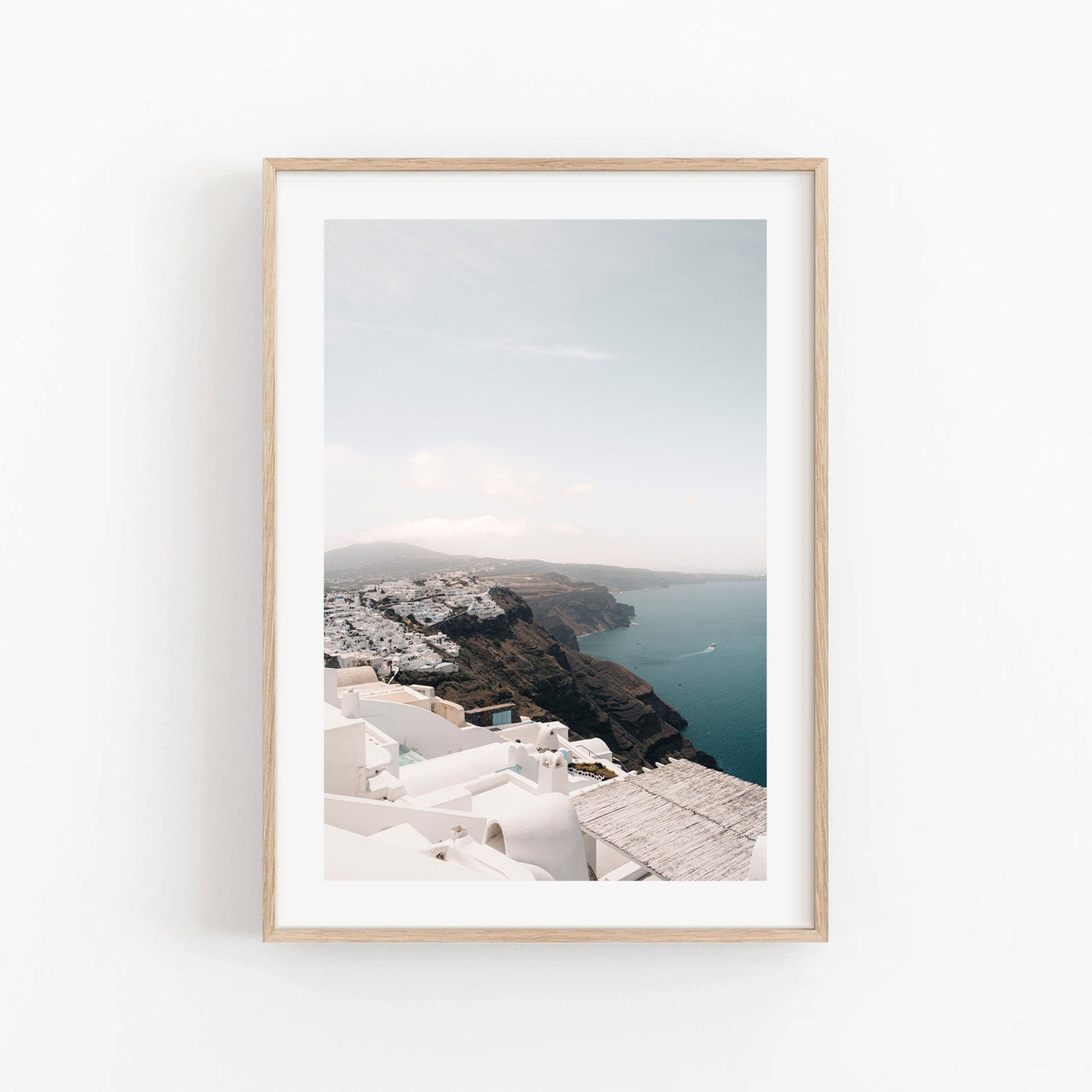 Framed photo Imerovigli: coastal village with white buildings, a sea view, and cliffs under a cloudy sky.
