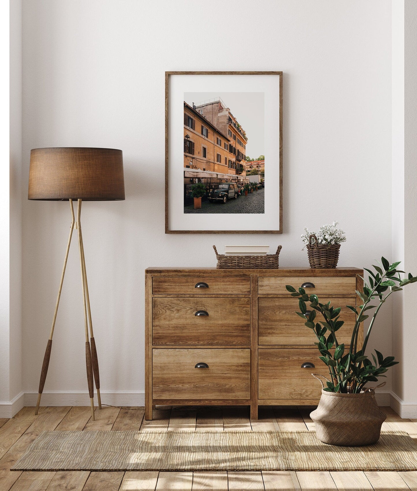 Cozy room featuring a wooden dresser, floor lamp, artwork, potted plant on a woven rug, and an Italian Car.