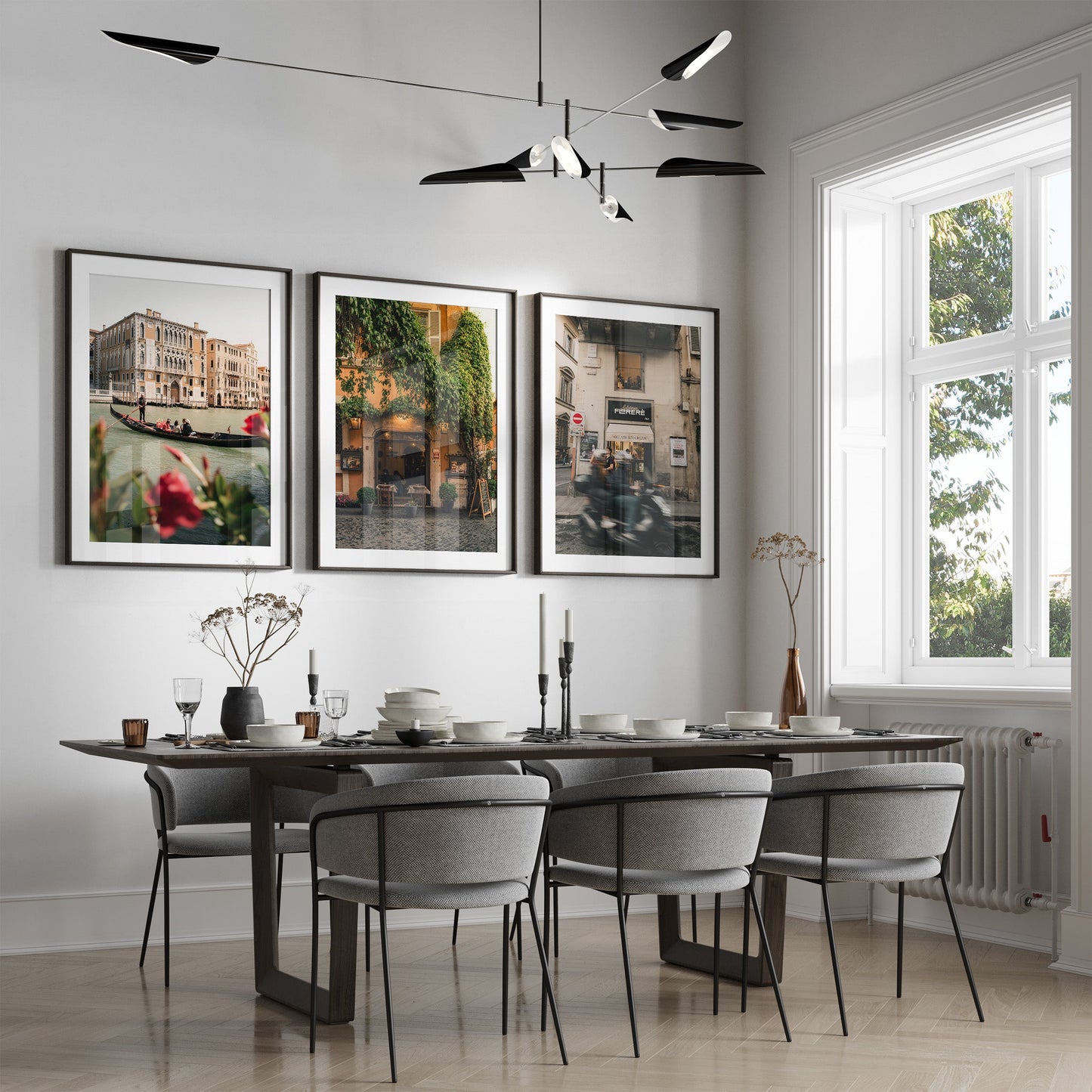 Modern dining room with six gray chairs, dark table, Italy - Set of 3 wall art, and a large window with natural light.