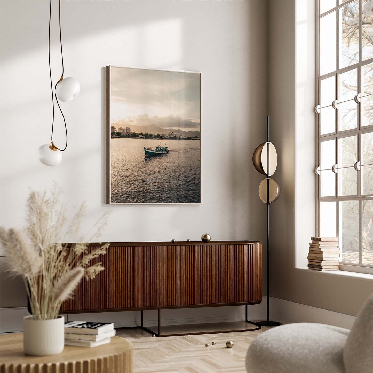 Modern living room with a large window, wooden cabinet, Kampot Boat painting on the wall, and pampas grass on the table.