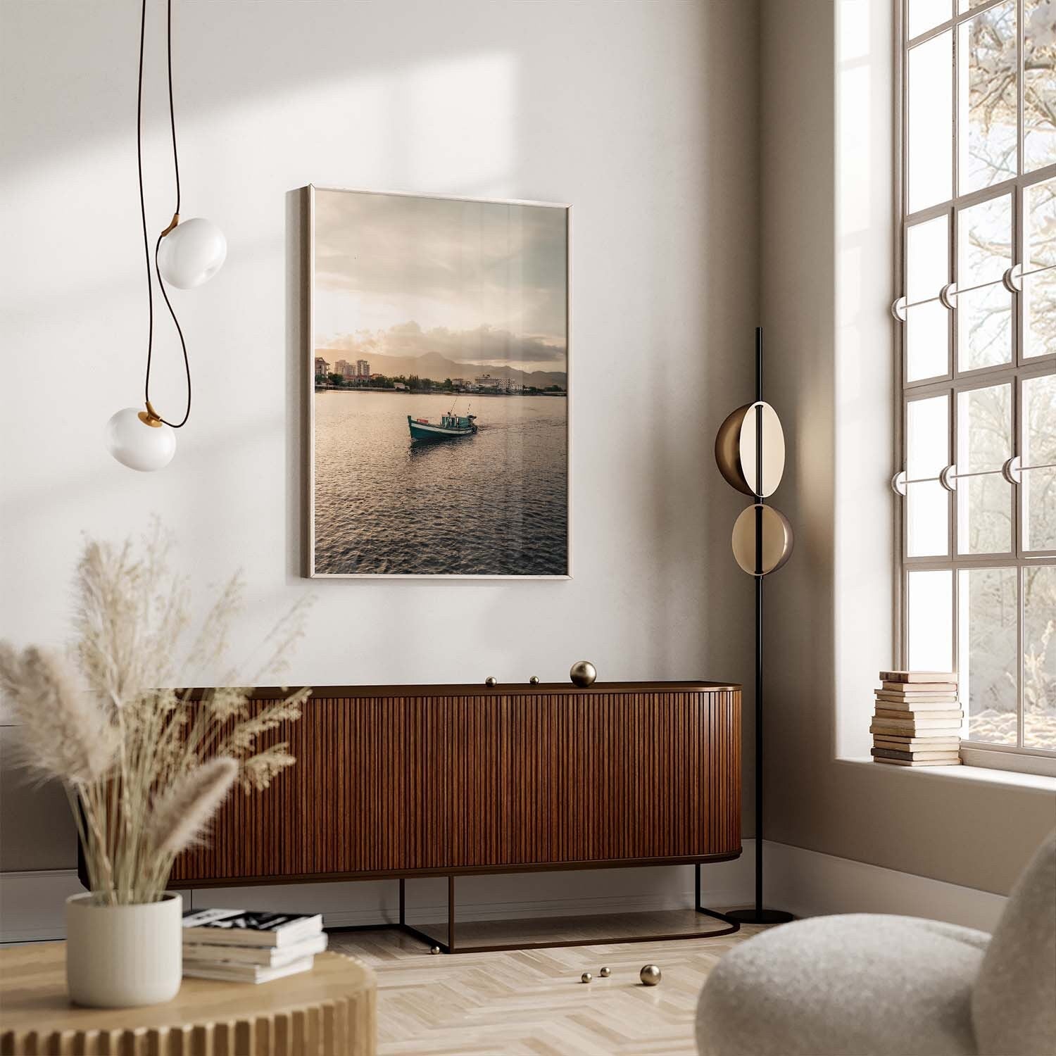 Modern living room with a large window, wooden cabinet, Kampot Boat painting on the wall, and pampas grass on the table.