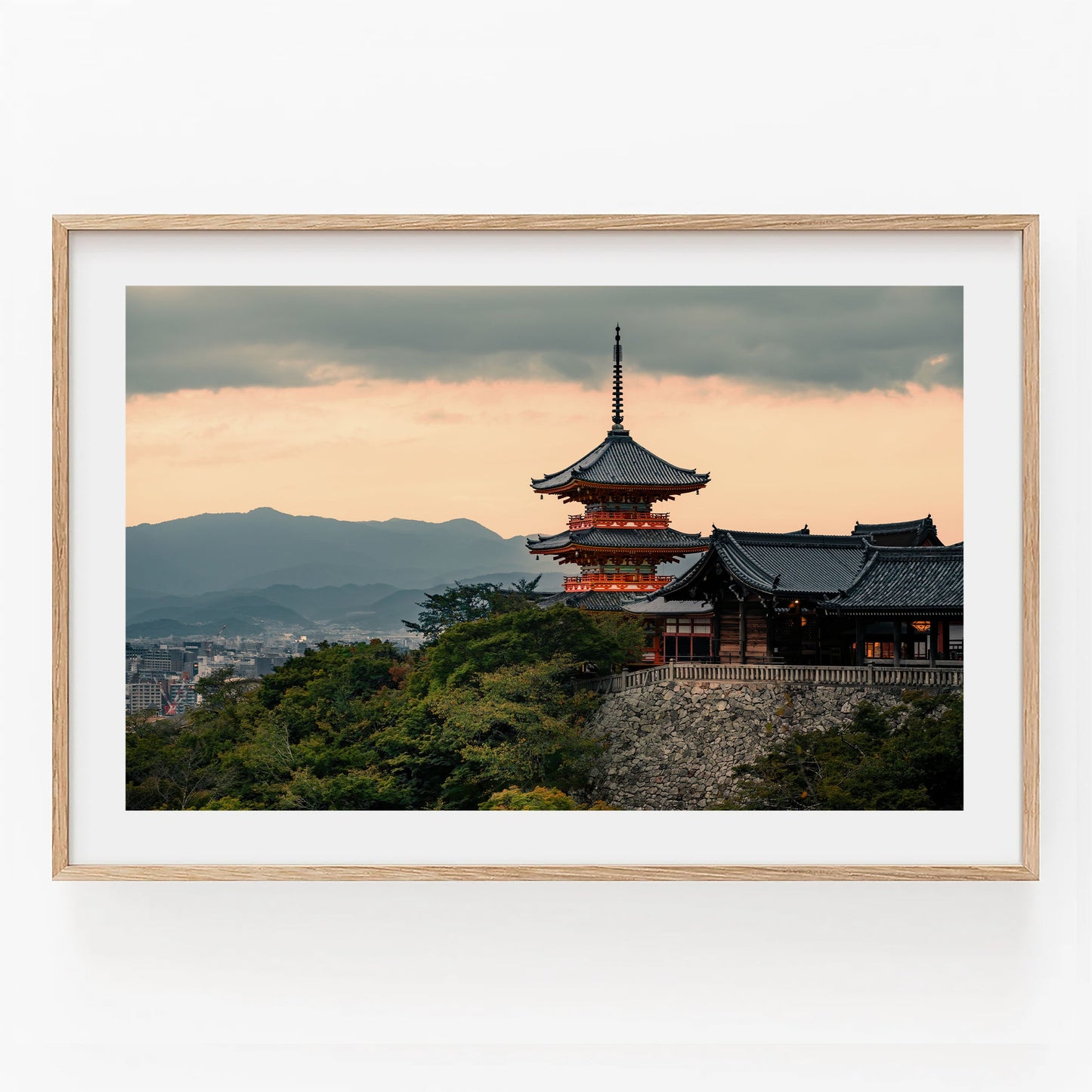 Kiyomizu-dera Sunset II: A light wood-framed Japanese pagoda at sunset with mountains and cityscape in the background.
