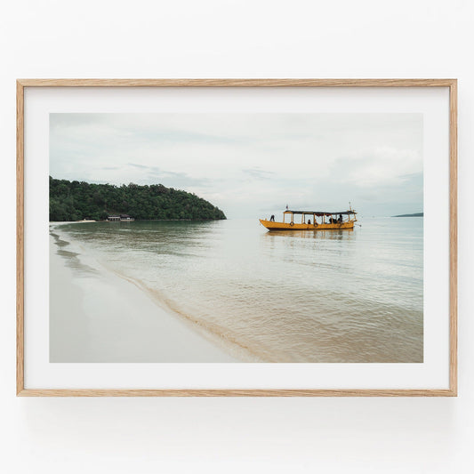 Framed photo titled Koh Rong featuring a yellow boat on calm water by a sandy beach with a green island backdrop.