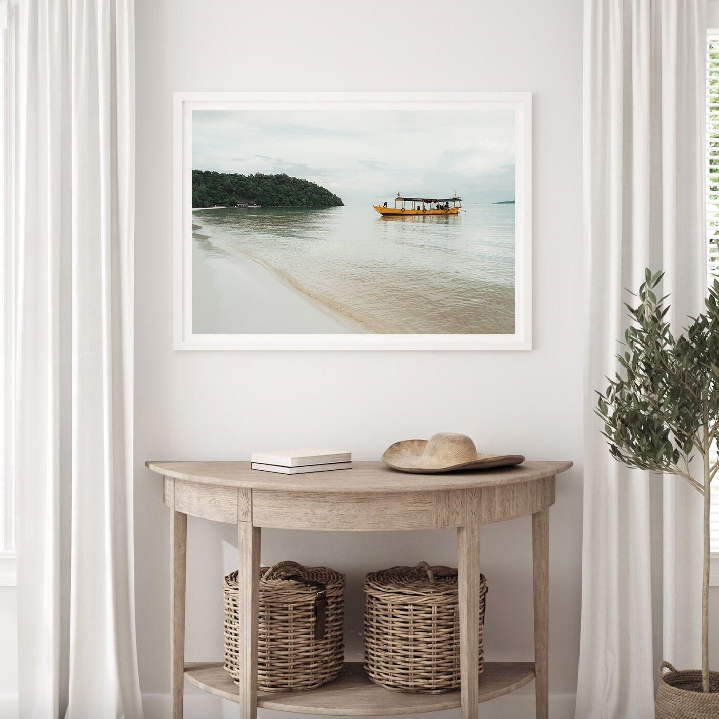 The Koh Rong framed photo hangs above a wooden table with baskets, next to white curtains.