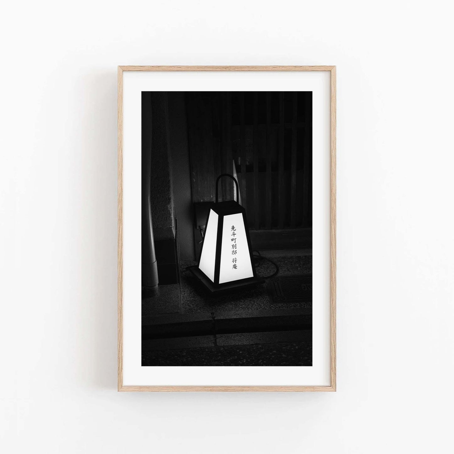 Kyoto Lantern I Black and White photo framed and hung on a white wall, featuring Japanese text.