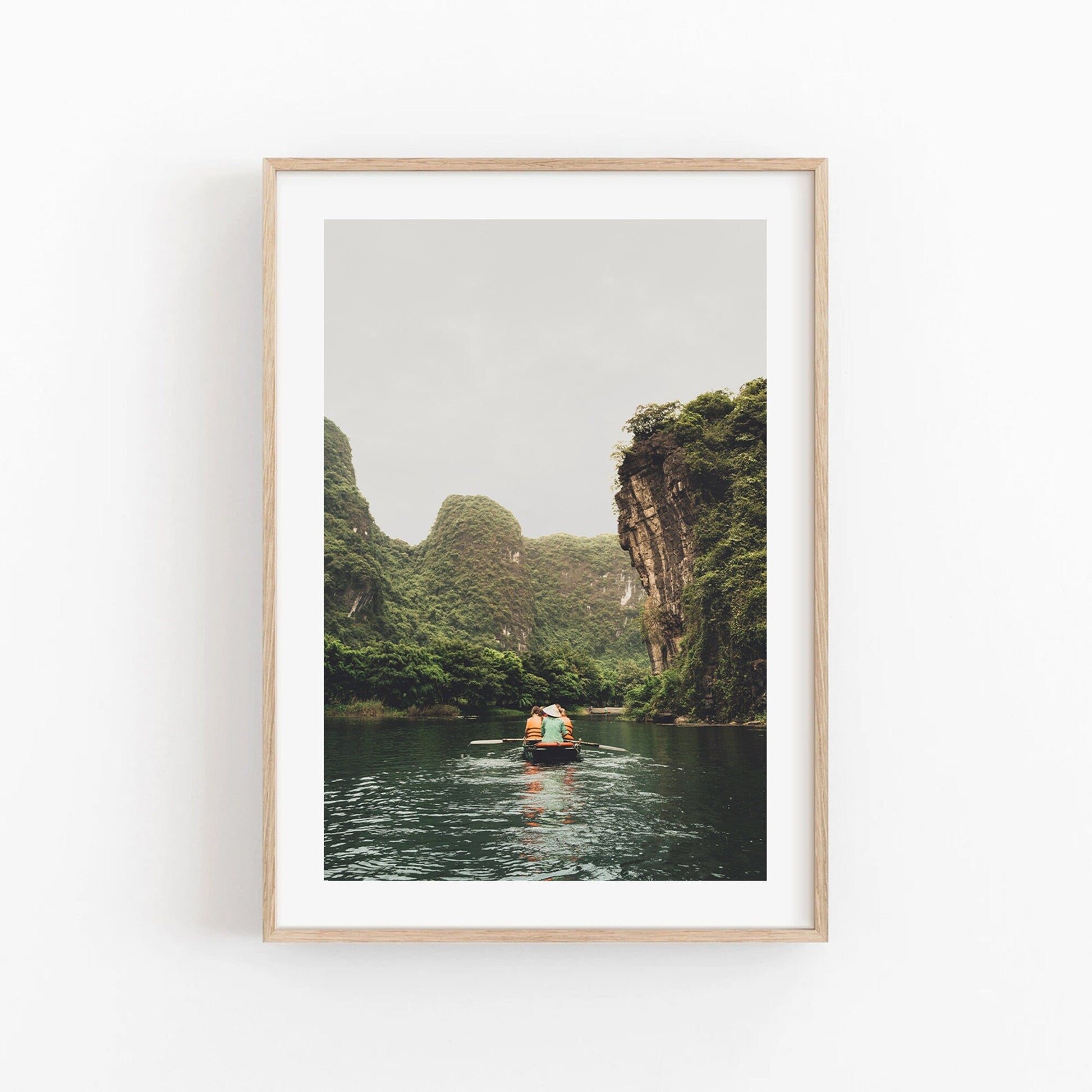 Framed Limestone Waterway: photo of a boat on a tranquil river amid lush cliffs under a cloudy sky.