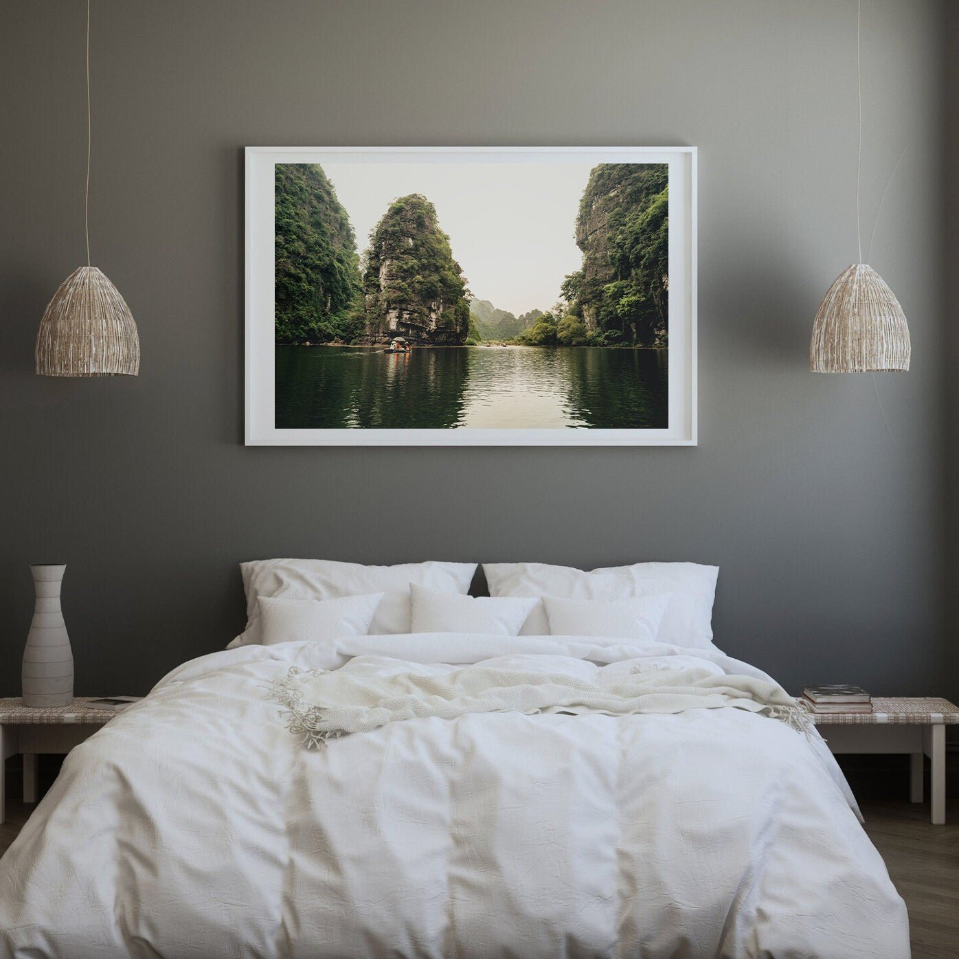 A bedroom with a large bed, neutral decor, and the Limestone Wonders framed above, depicting a serene river scene.
