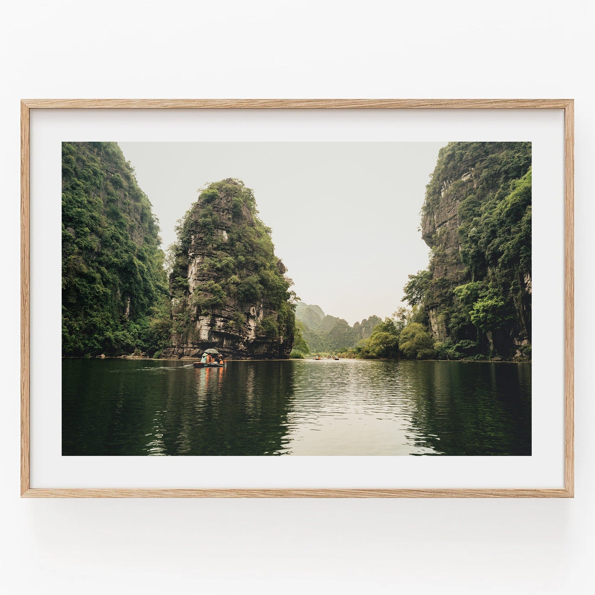 Framed art Limestone Wonders features a tranquil river scene with green cliffs and a small boat.