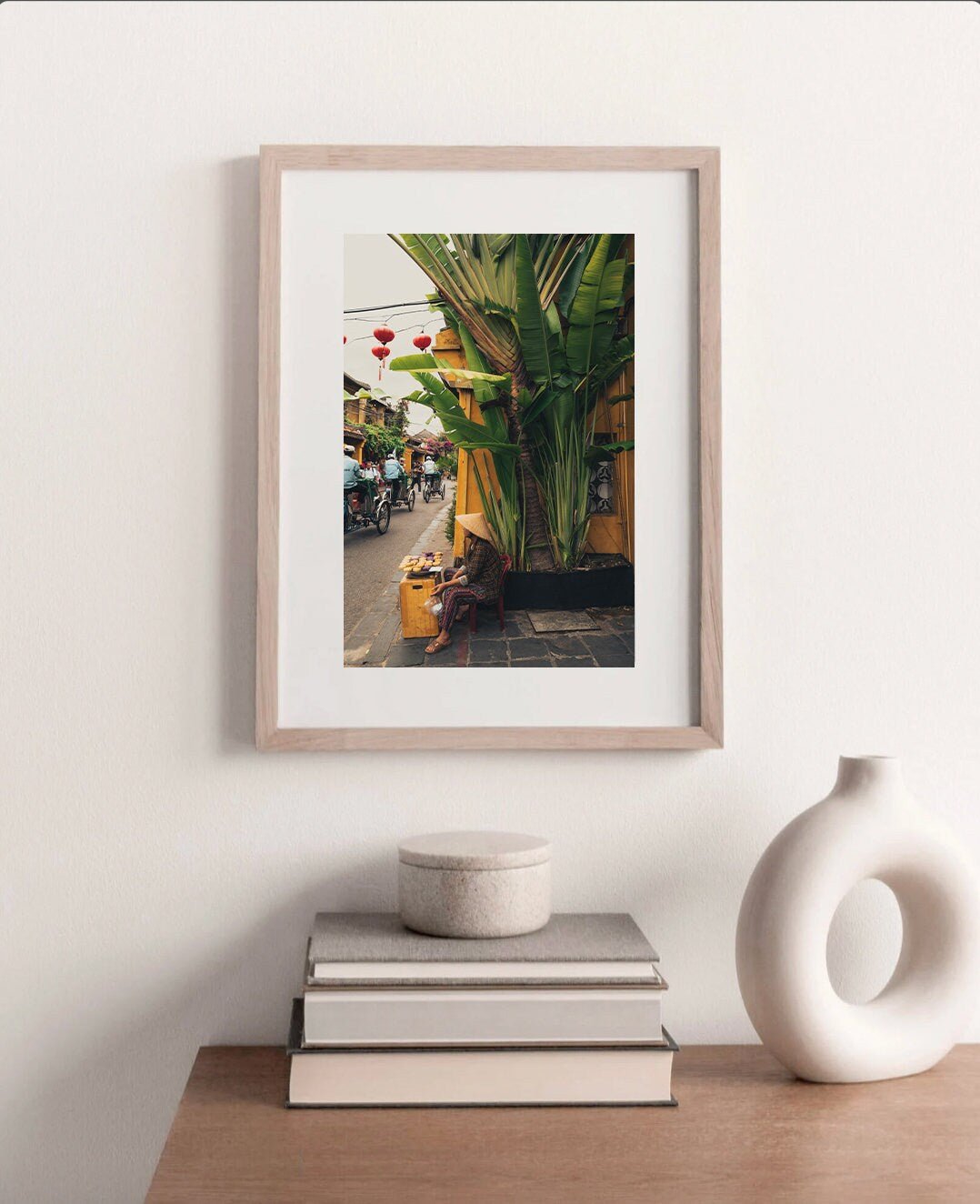 Local Vendor photo on a white wall above a table with books and a white vase.