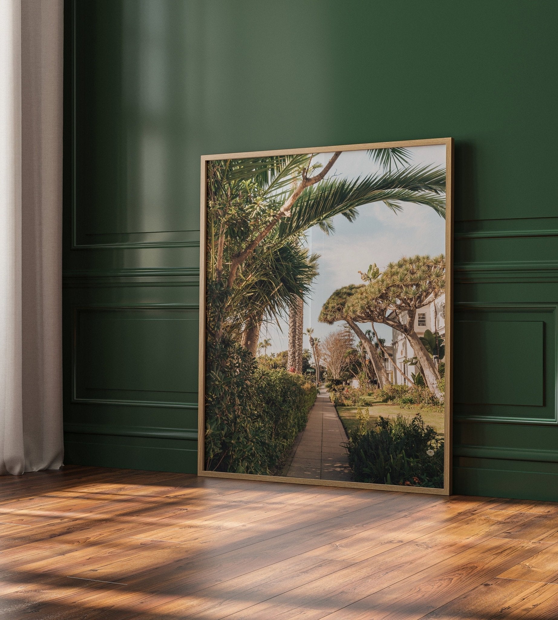 Framed painting Loma Lane against a dark green wall on a wooden floor.