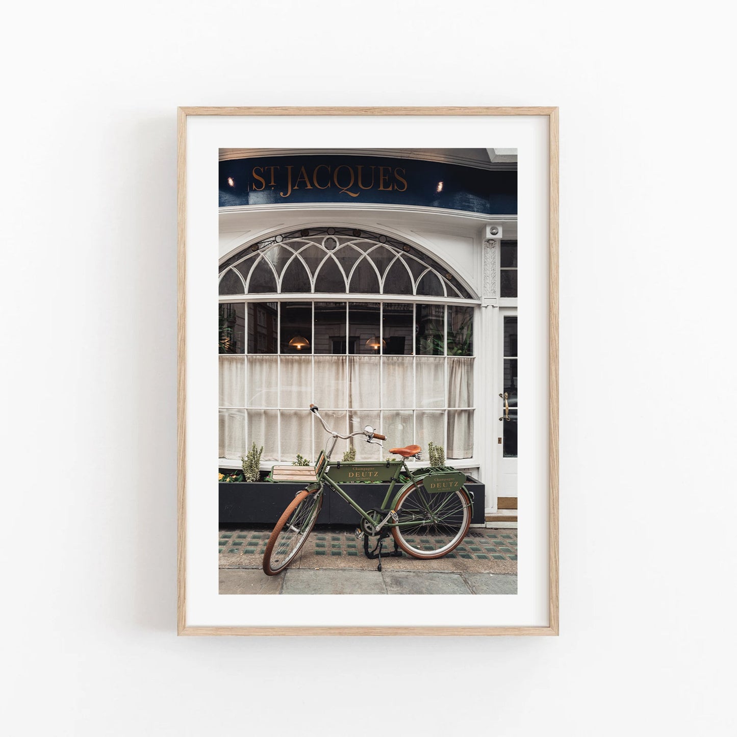 Framed photo of a London Bike by a café with arched windows and St Jacques sign.