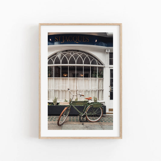 Framed photo of a London Bike by a café with arched windows and St Jacques sign.