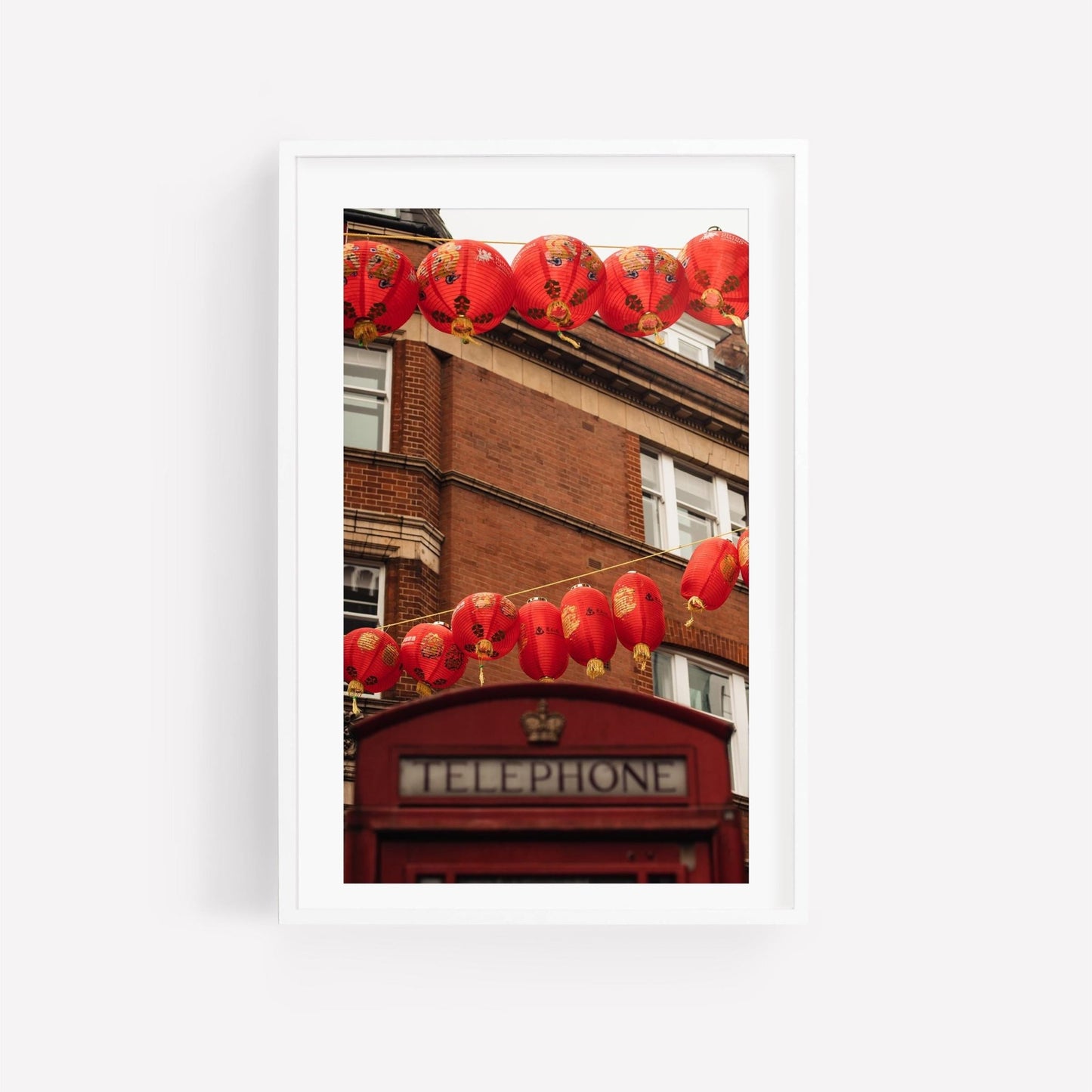 London Chinatown: Red lanterns adorn a classic red telephone booth in front of a brick building.