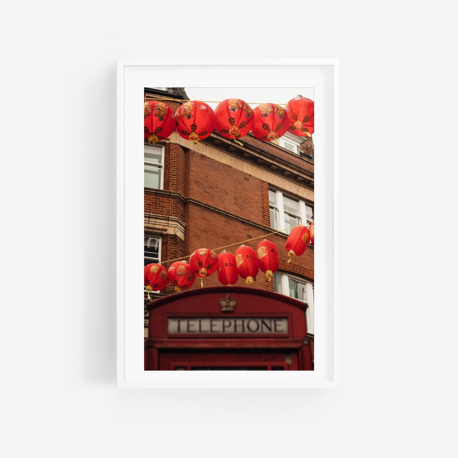 London Chinatown: Red lanterns adorn a classic red telephone booth in front of a brick building.