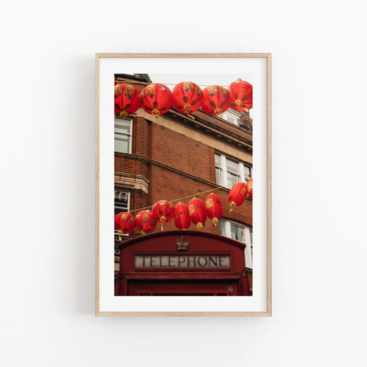 Framed photo of London Chinatown featuring red lanterns, a classic red phone booth, and a brick building.