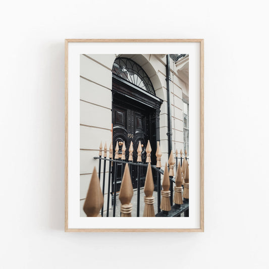 Framed photo titled London Door showing a classic arched doorway with a decorative iron fence and gold spikes.