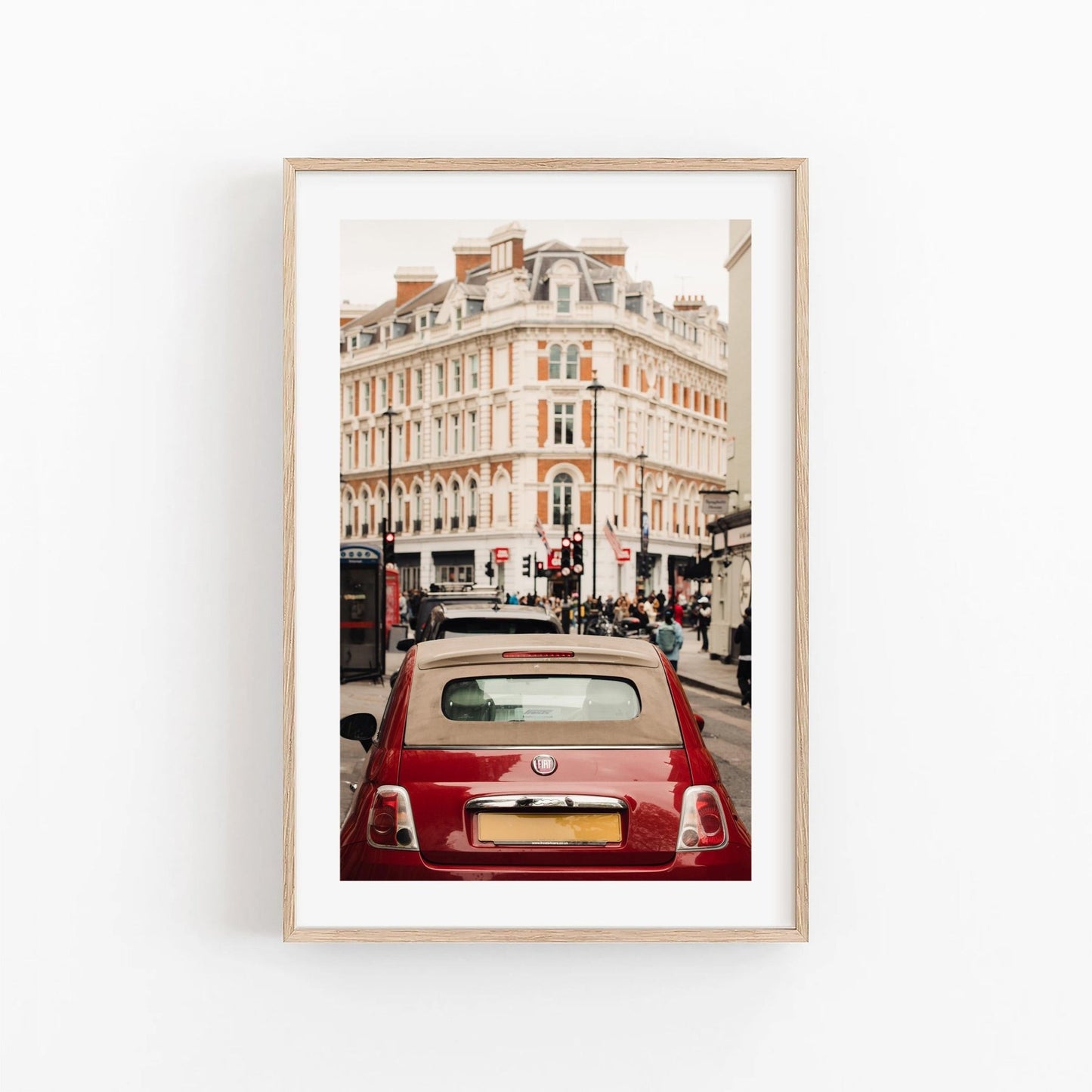 Framed photo of the London Fiat, featuring a red car on a street with historic buildings.