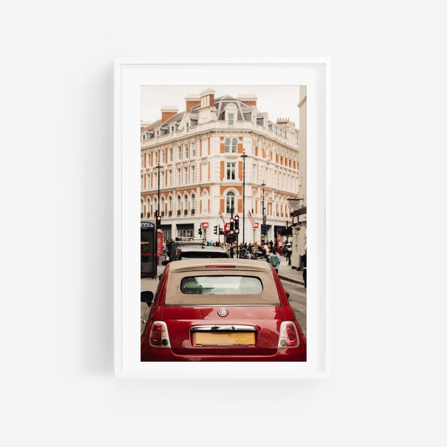 A London Fiat on a city street with a historic building and pedestrians in the background.
