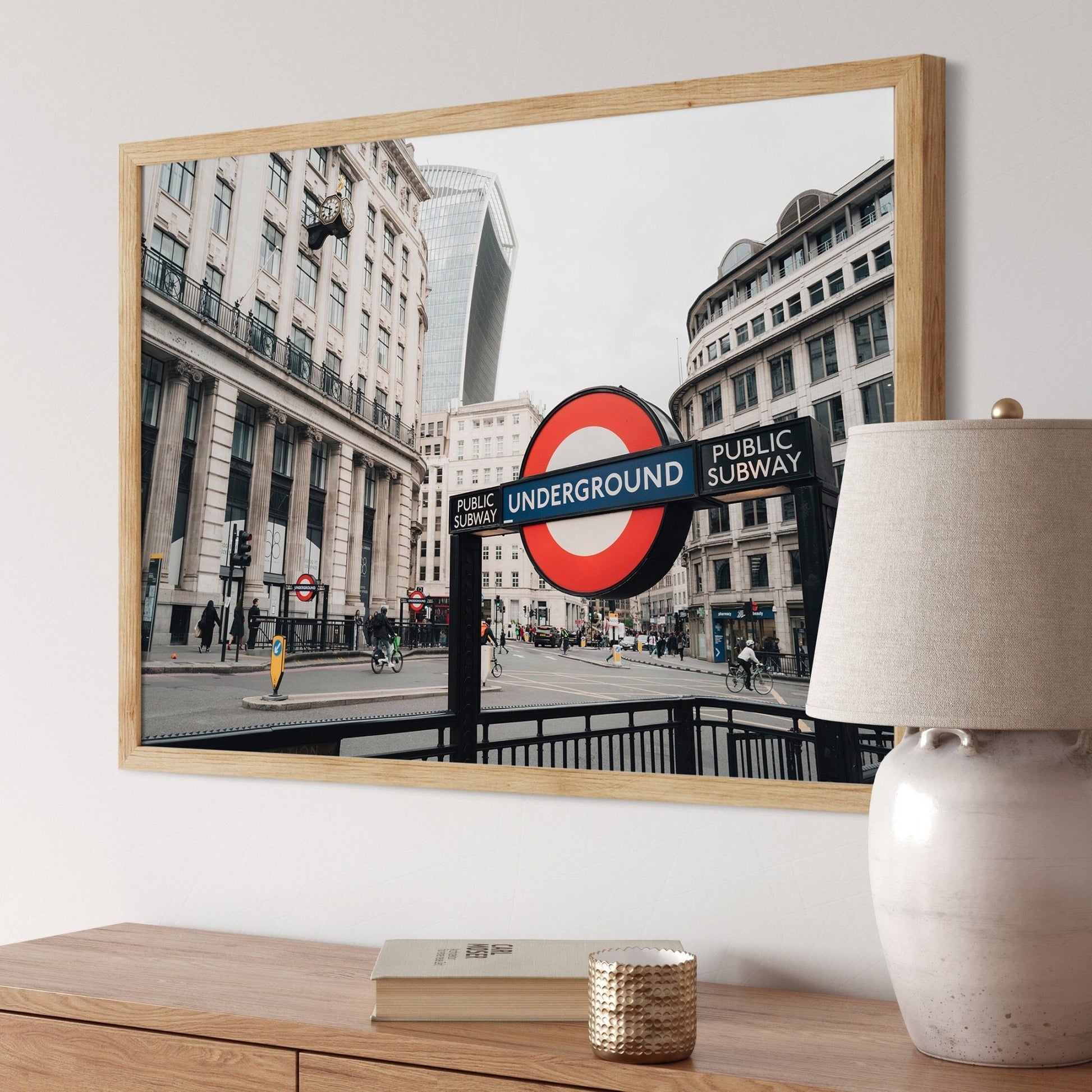 London Tube sign photo framed on a wall above a wooden table with a lamp and decor.