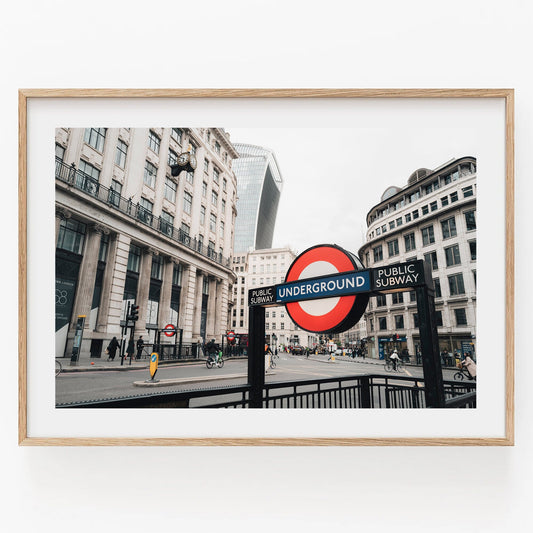 Framed photo of the London Tube with city buildings and pedestrians in the background.
