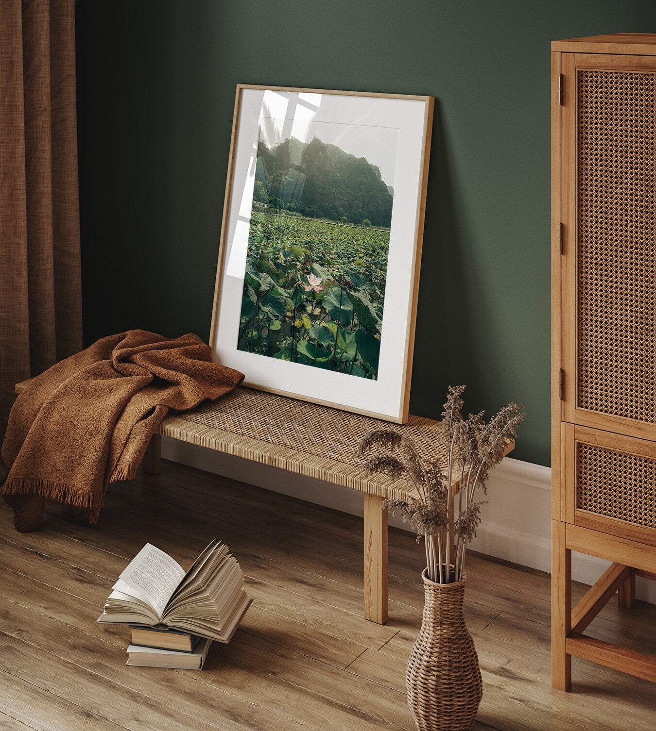 Cozy room with Lotus Lake photo on a bench, book on floor, brown throw, and dried flowers in vase.