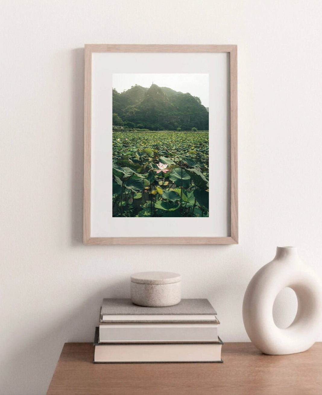 Lotus Lake photo of a lily pond and mountains, framed and displayed above books and a decorative vase.