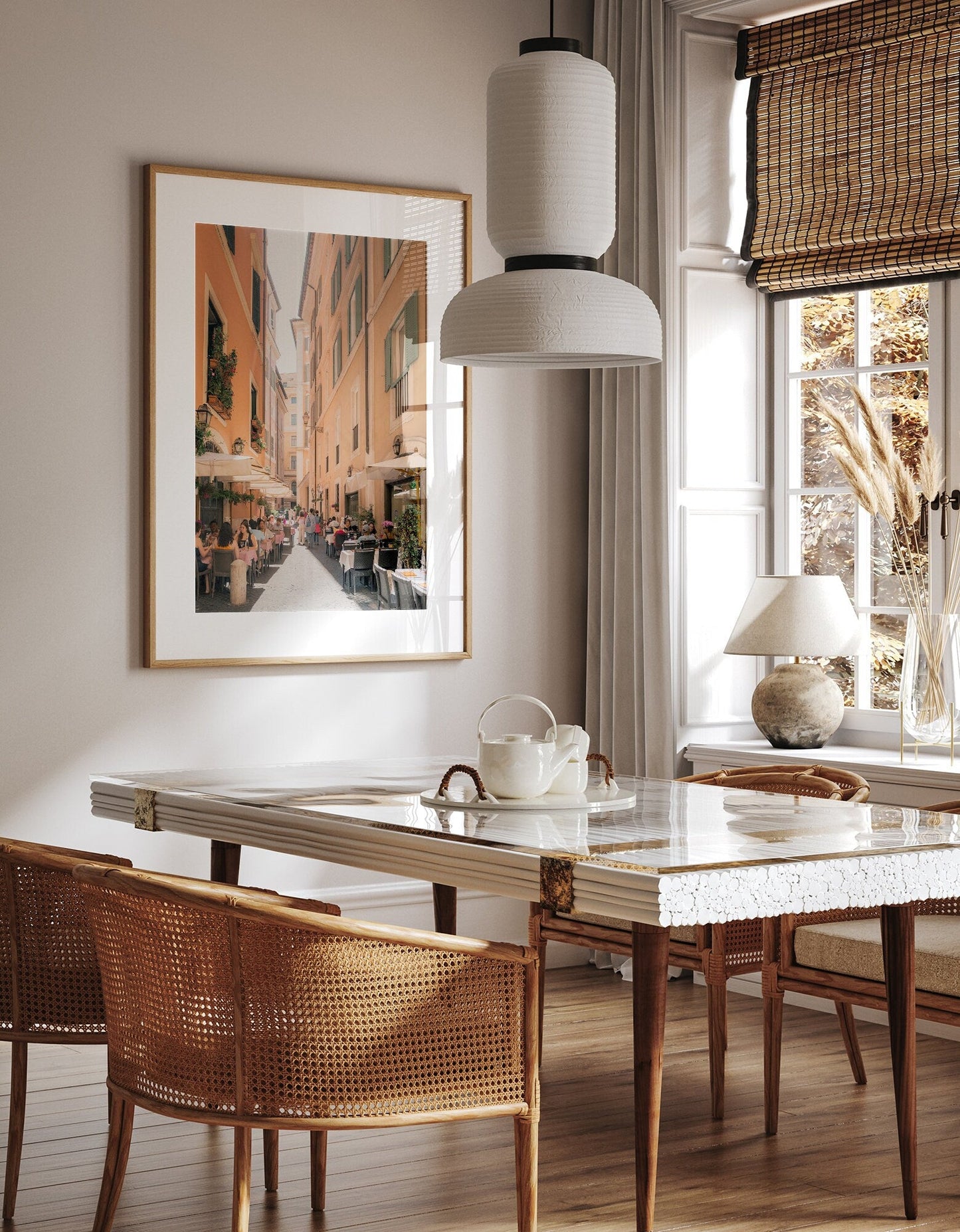 Minimalist dining room with a marble table, wicker chairs, and Lunch in Rome, a large framed street view painting.