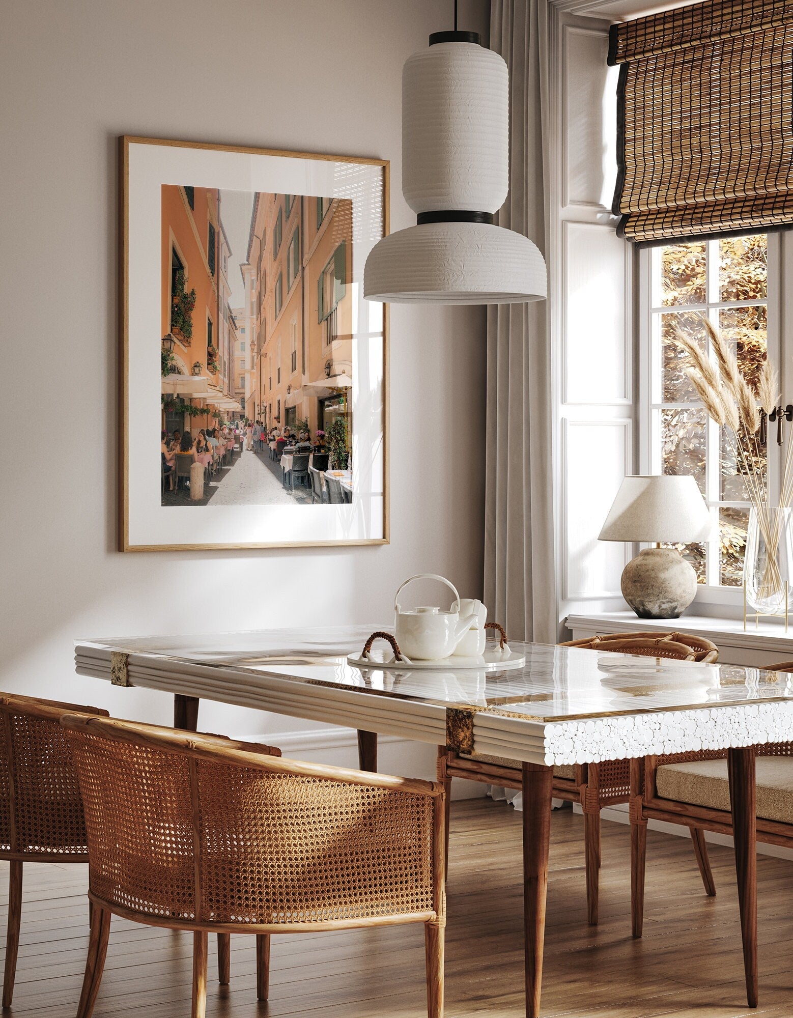 Minimalist dining room with a marble table, wicker chairs, and Lunch in Rome, a large framed street view painting.