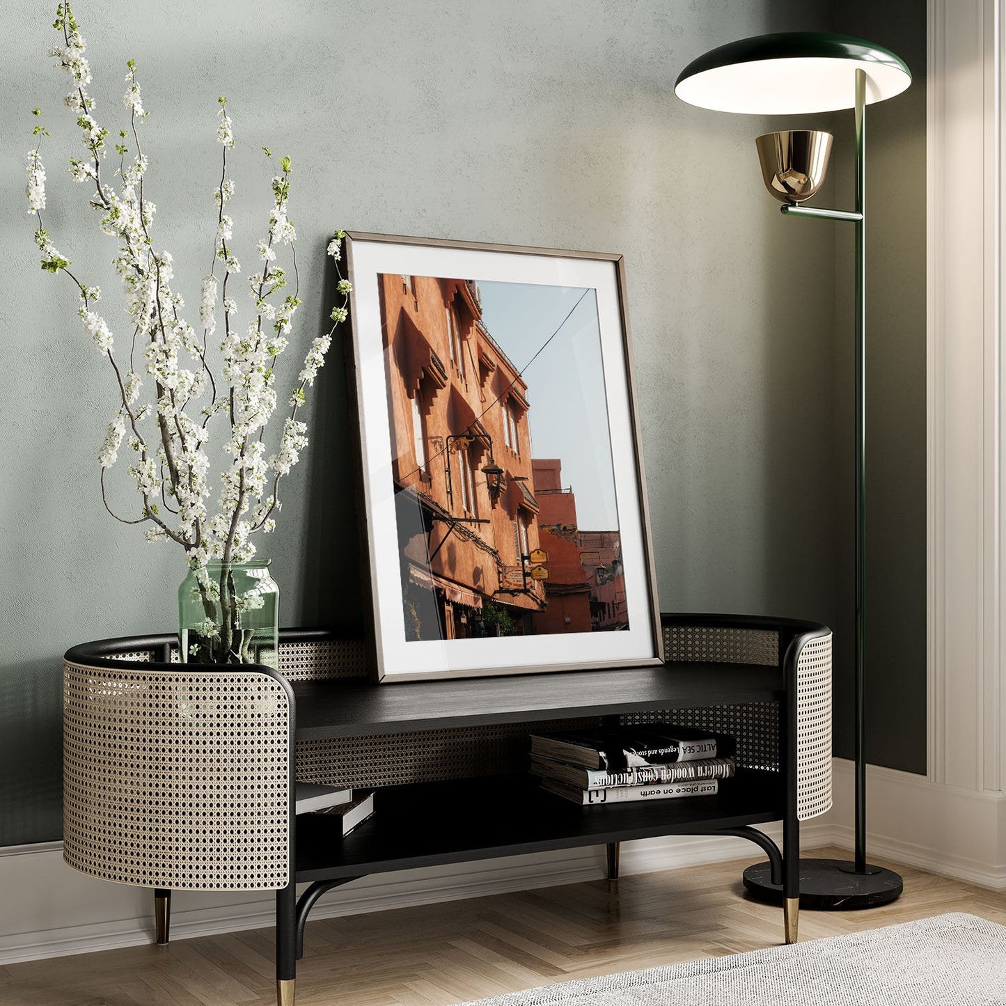A stylish room with a Marrakesh Red Building art, a tall lamp, and a vase of white flowers on a bench.